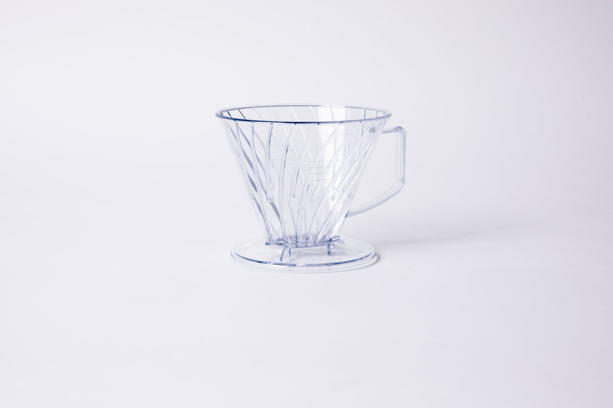 Clear plastic ribbed cone shaped dripper with a flat bottom base and handle. Set on a light gray background