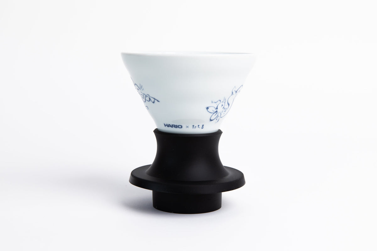 white cone-shaped coffee dripper with blue colored animal design in a black silicone base. set on a white background
