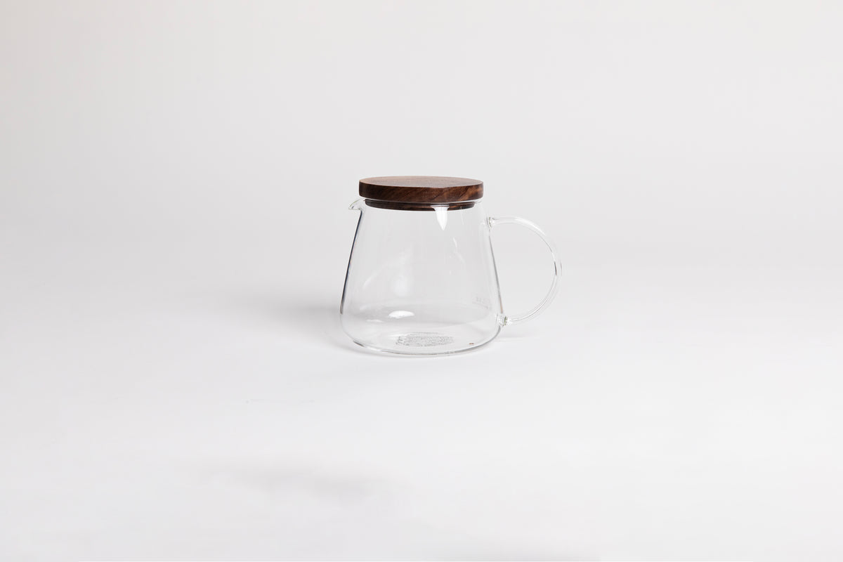 tulip shaped glass decanter with glass handle and spout. Topped with a walnut wood lid. set on a white background.