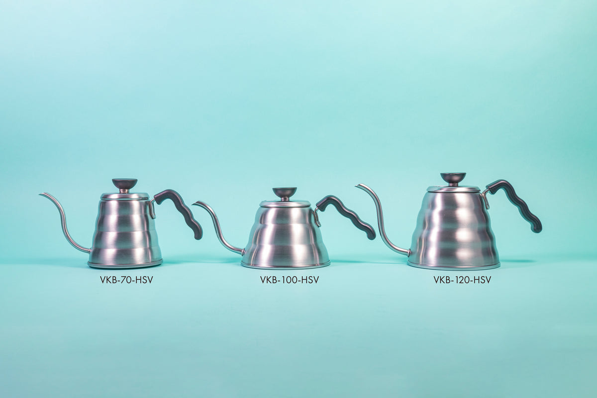 Three silver beehive-shaped stainless steel kettles of varying sizes with wave-shaped black plastic handles and round black plastic lid knobs with flat tops set against a light blue background.