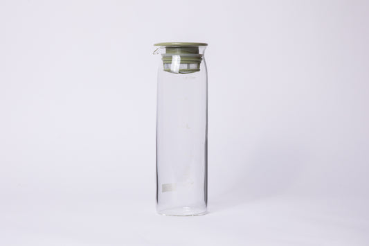cylindrical tall glass with fluted spout with a light green filter lid. set on a white background