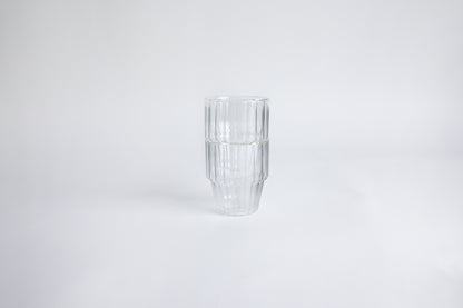2 ribbed glass cups stacked on top of each other. set on a white background.