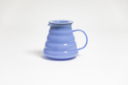 All glass milky purple beehive shaped coffee server with handle and glass lid on white backdrop