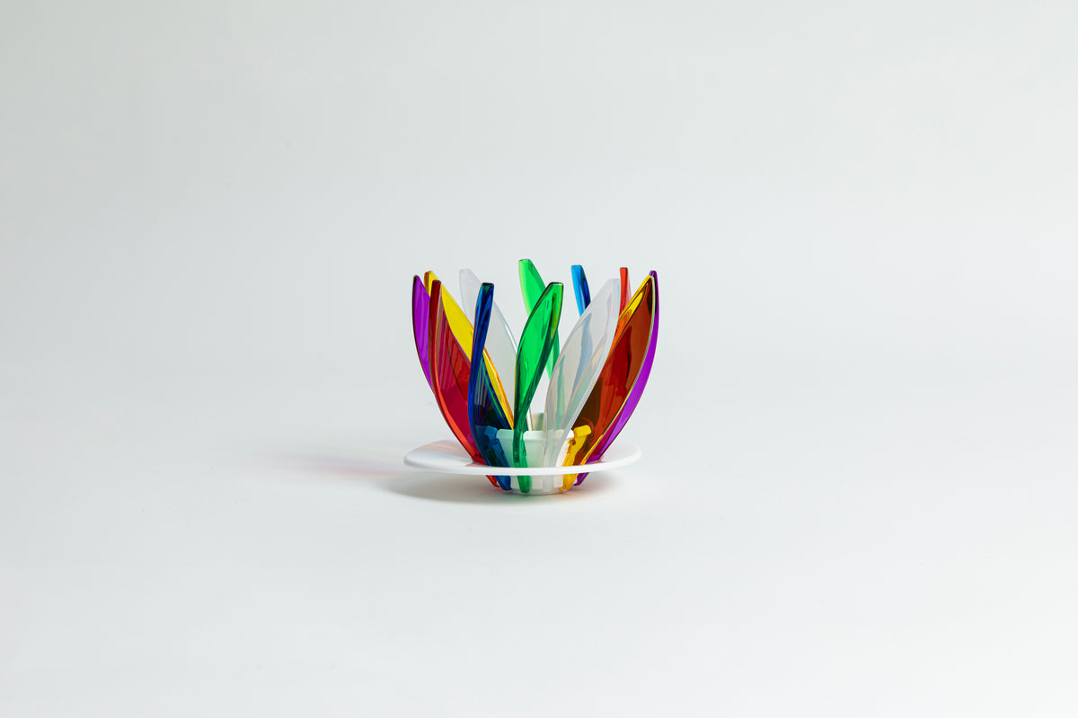 Transparent rainbow in the colors red, blue, green, white, orange, purple and yellow pedals in a spiral shape on a transparent black base on a white background.
