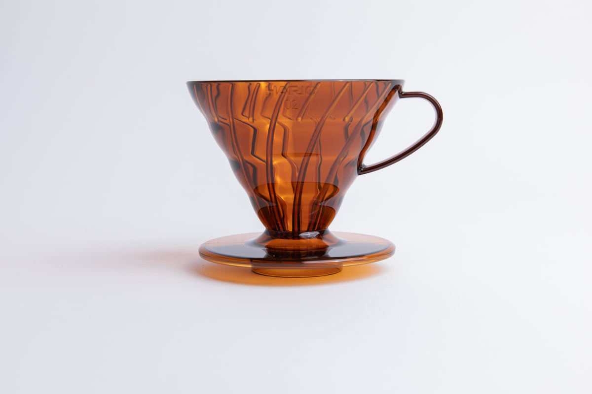 Transparent orange plastic cone coffee dripper with handle on a white background