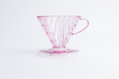Transparent pink plastic cone coffee dripper with handle on a white background
