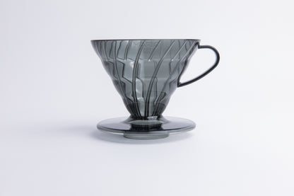 Transparent gray plastic cone coffee dripper with handle on a white background
