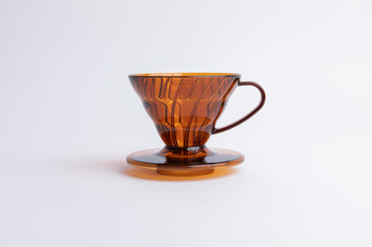 Transparent orange plastic cone coffee dripper with handle on a white background