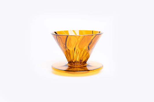 transparent orange plastic cone dripper on white background.