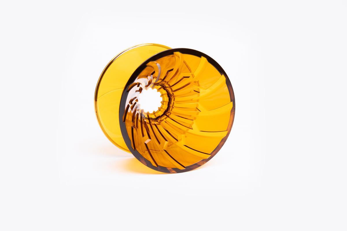transparent yellow plastic cone dripper with interior ribbing on a white background