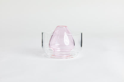 Dome-shaped pink clear glass matcha whisk holder with a smooth, tapered form, placed inside a clear glass base. Displayed on a white background with 'Hario' branding