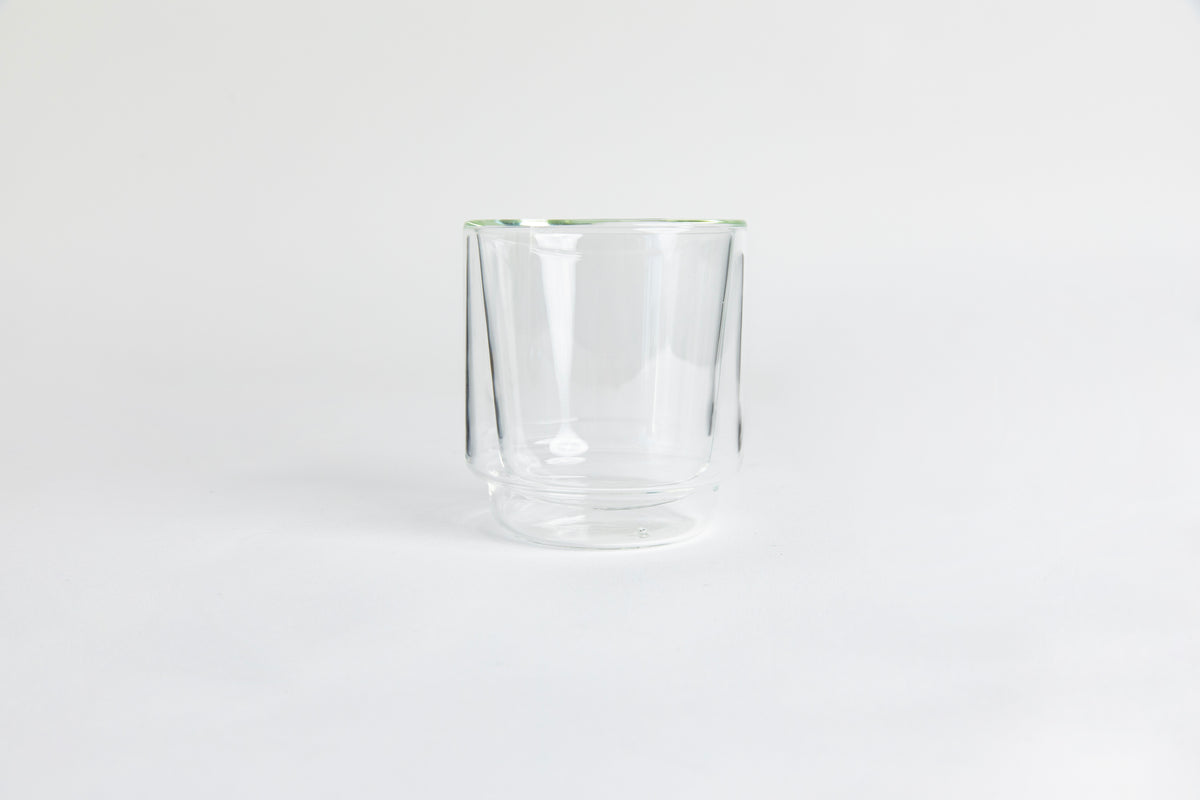 A clear double-walled glass cup. set on a white background