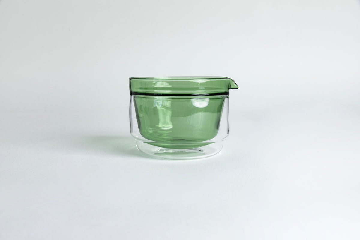 Double-walled glass cup with green interior. set on a white background.