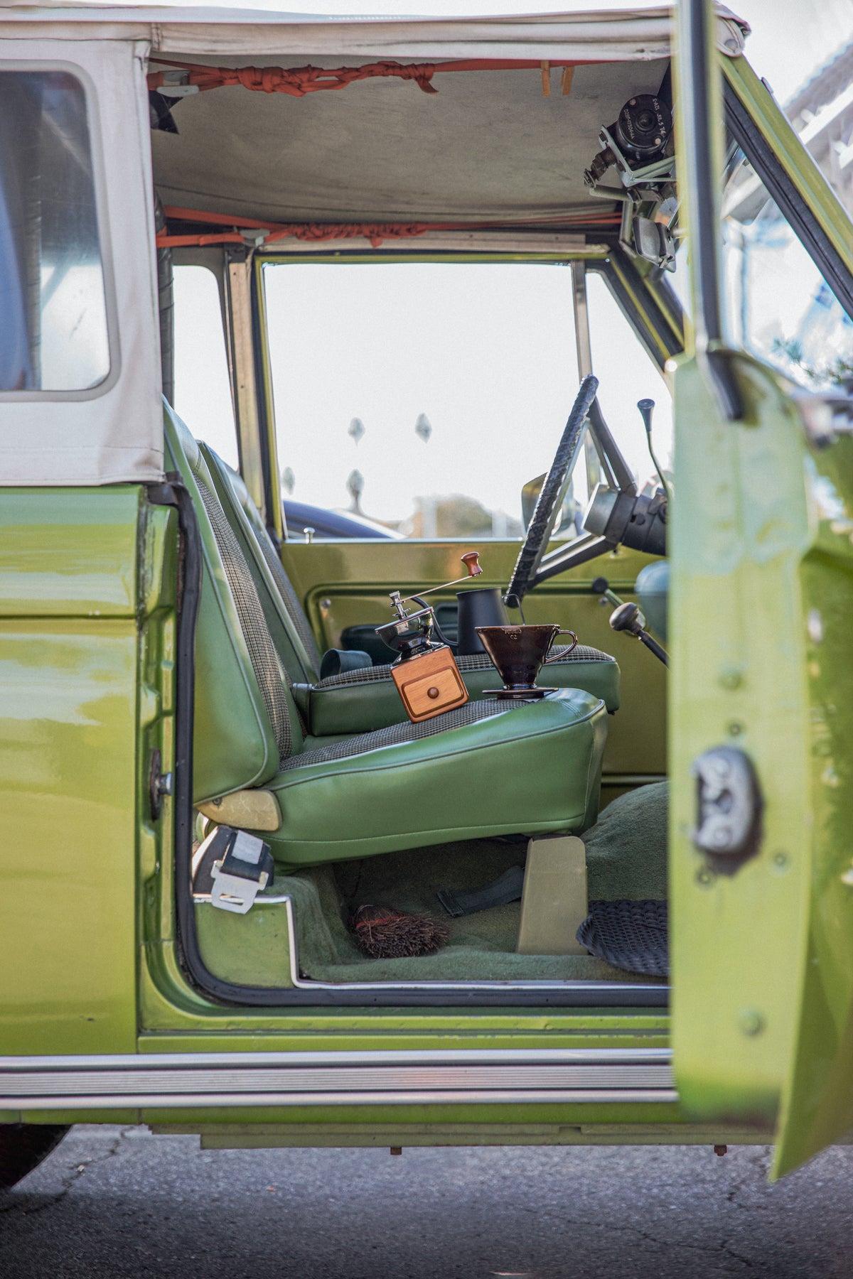 Vintage green bronco interior with a hand mill and brown coffee dripper in the seat.