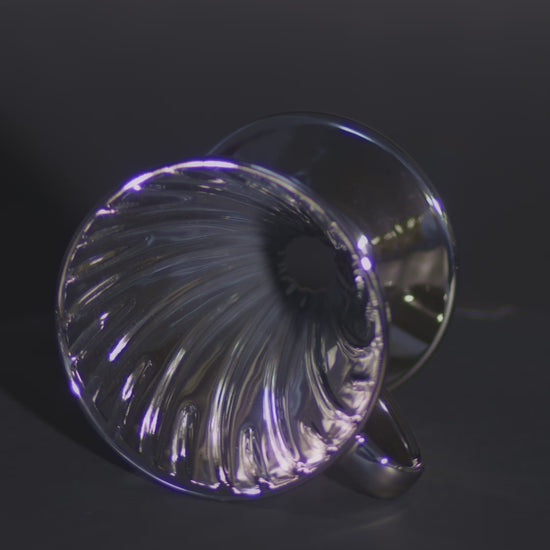 A metallic silver cone lying on its side, spinning to showcase the ribbed interior design.