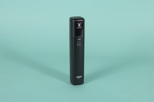 Black monolithic rubberized black plastic device with black screen and a single rounded square button.