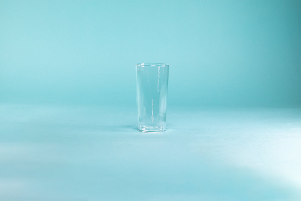 Thin, tall glass tumbler against a blue background.