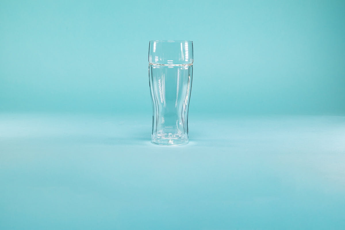 Double wall clear beer glass on a blue background.